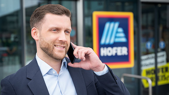 Regionalverkaufsleiter telefoniert vor Filiale